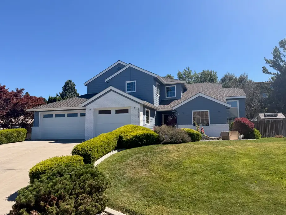 Two-story Kennewick home repainted blue-grey with white trim and a three-car garage