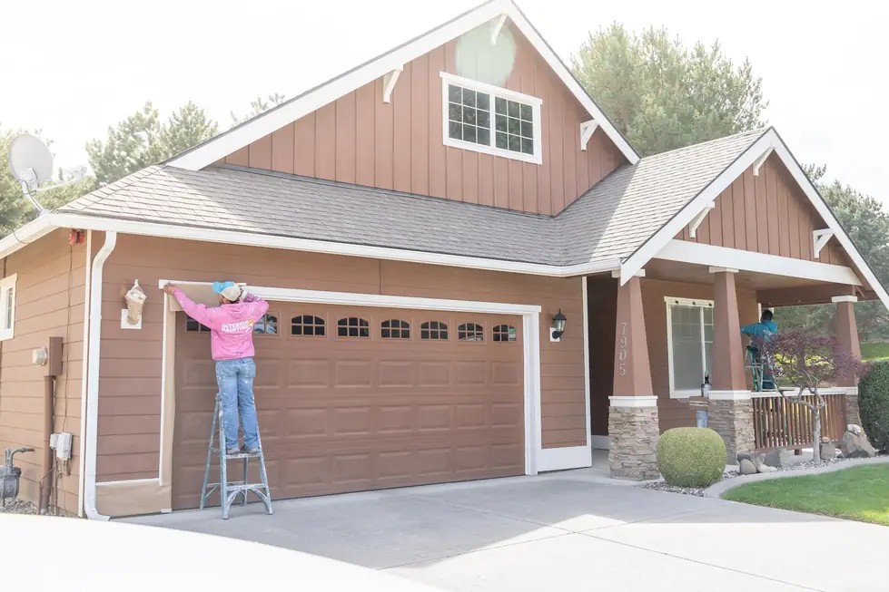 Smile-A-Mile crew on ladders painting trim on a brown board-and-batten home